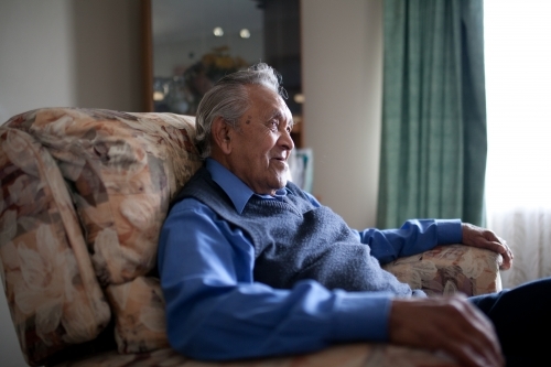 Elderly aboriginal man sitting in lounge chair at home