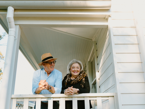 Elderly couple leaning against the wooden rails on the porch - Australian Stock Image