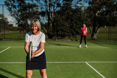 Elderly female tennis player prepares to hit the ball - Australian Stock Image