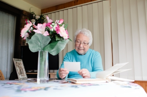 Elderly lady browsing through photographs - Australian Stock Image