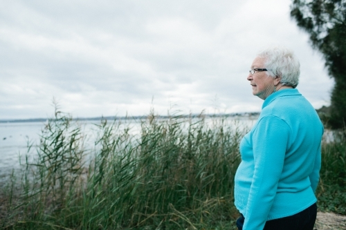 Elderly lady looking out towards a lake - Australian Stock Image