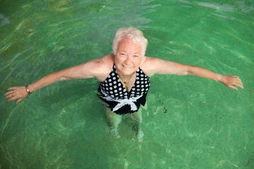 Elderly lady relaxing in a swimming pool - Australian Stock Image