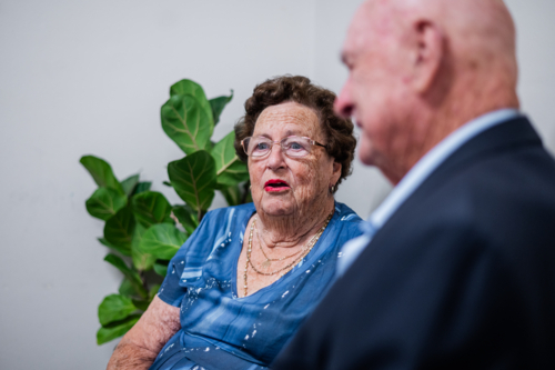 Elderly man and woman sharing a conversation while seated on the chair indoors - Australian Stock Image
