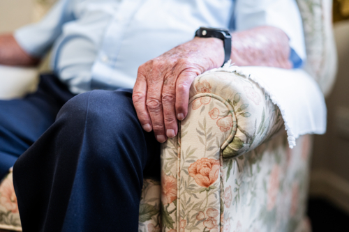 Elderly man sitting comfortably on a patterned armchair indoors - Australian Stock Image