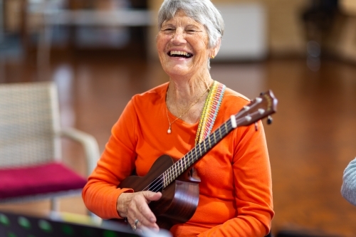 elderly woman holding ukulele and laughing