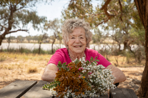 Elderly woman outside with wild flowers - Australian Stock Image