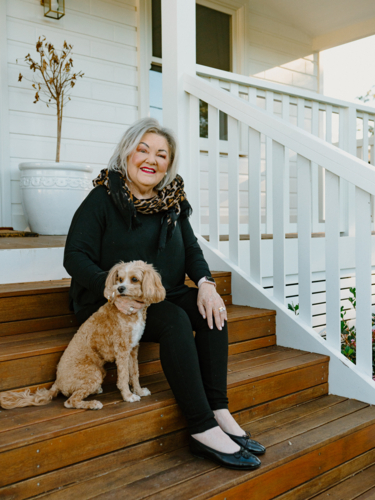 Elderly woman sitting on the wooden steps with her small dog. - Australian Stock Image