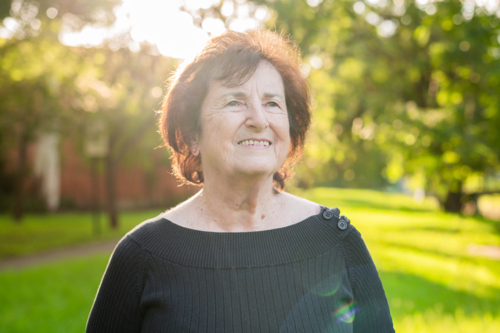 Elderly woman standing outdoors with soft sunlight glow - Australian Stock Image