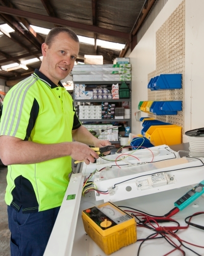 Electrician testing power board in his workshed - Australian Stock Image