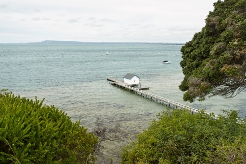 Elevated view of long wooden jetty with boatshed at end