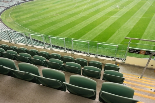 Empty stadium seats and a green afl oval - Australian Stock Image