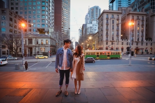 Engaged couple embracing in the city with Melbourne cityscape in background at night - Australian Stock Image