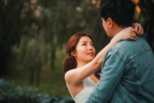 Engaged couple embracing in tree lined avenue in Melbourne's Treasury Gardens - Australian Stock Image