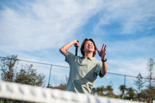 Enthusiastic young man prepares to smash a tennis ball during practice on a warm afternoon - Australian Stock Image