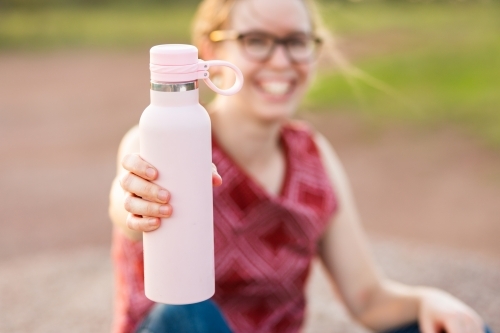 environmentally friendly re-usable drink bottle held by active young woman outside - Australian Stock Image