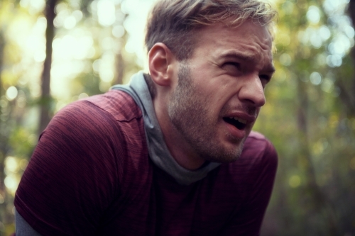 Exhausted man catching breath on Morning Run in the Woods / Forest / Bush - Australian Stock Image