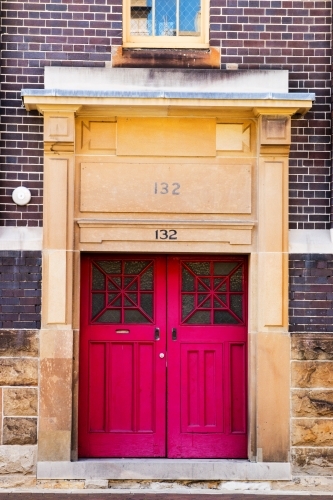 Faded red doors in stone and brick building