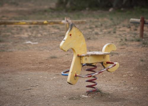 Faded yellow rocking horse at park playground