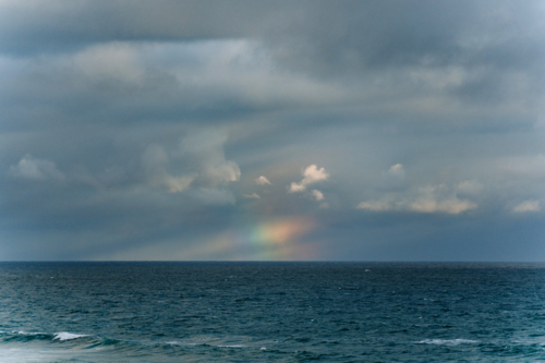 Faint rainbow glowing above the ocean horizon - Australian Stock Image