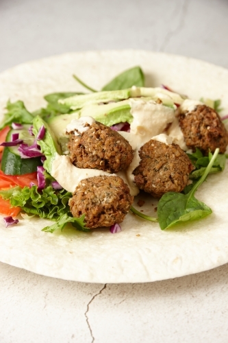 Falafel wraps with meatballs, vegetables, and dressing - Australian Stock Image