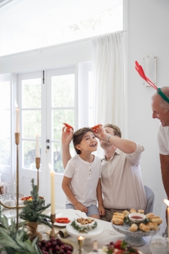 Family at Christmas table making jokes with prawns - Australian Stock Image