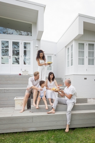 Family eating snacks on backyard stairs