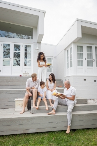 Family eating snacks on backyard stairs - Australian Stock Image
