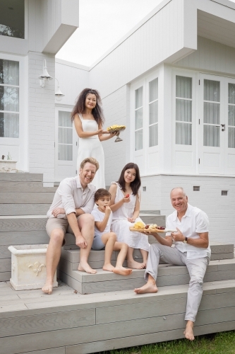 Family eating snacks on backyard stairs - Australian Stock Image