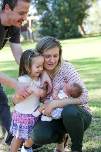 Family group with a new-born baby in a green, shady park - Australian Stock Image