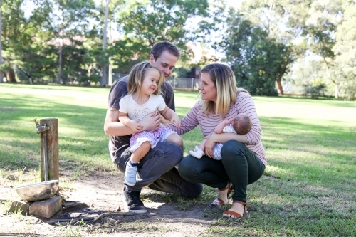 Family group with a new-born baby in a green, shady park - Australian Stock Image