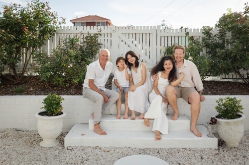 Family of five sitting on backyard steps