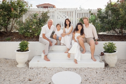 Family of five sitting on backyard steps - Australian Stock Image