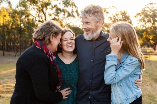 Family of four with adult children looking at one another laughing - Australian Stock Image