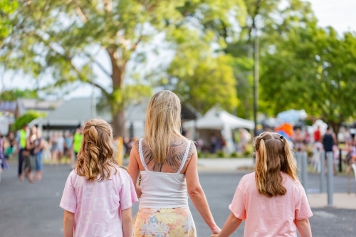 Family of three walking through crowds at local public event - Australian Stock Image