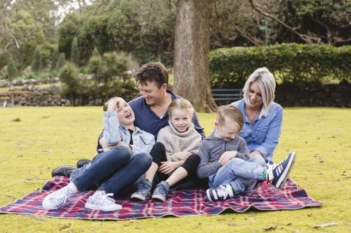 Family on picnic blanket laughing