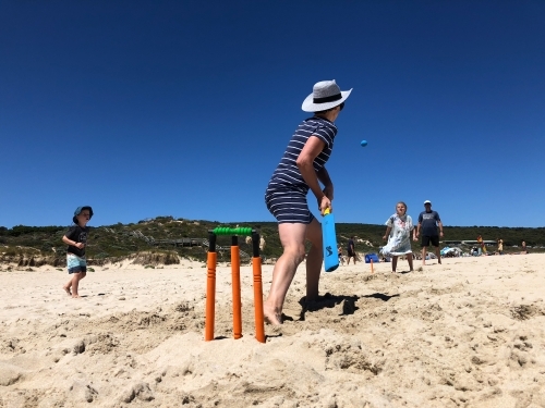 Family playing cricket at the beach in the sand - Australian Stock Image