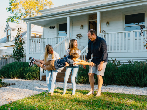 Family playing in the front yard of the house. - Australian Stock Image