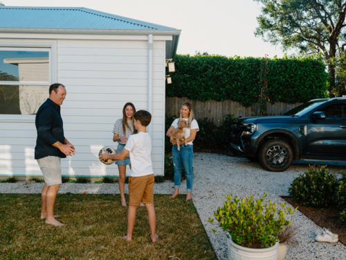 Family playing with a soccer ball in the garden. - Australian Stock Image