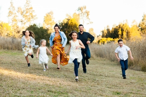 Family running together through park - Australian Stock Image
