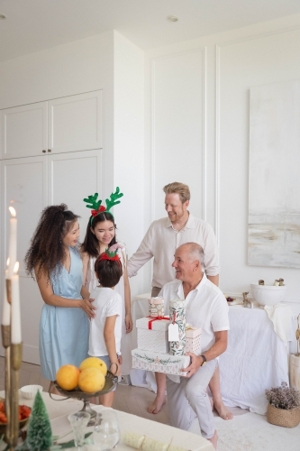 Family talking with grandad holding pile of presents - Australian Stock Image