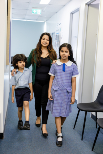 Family walking down hallway in doctor's office - Australian Stock Image