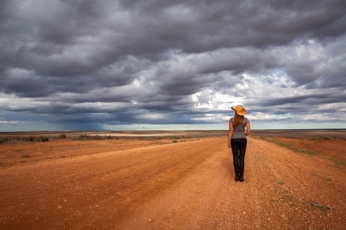 Farm woman watches the storm over an arid desert landscape outback Australia