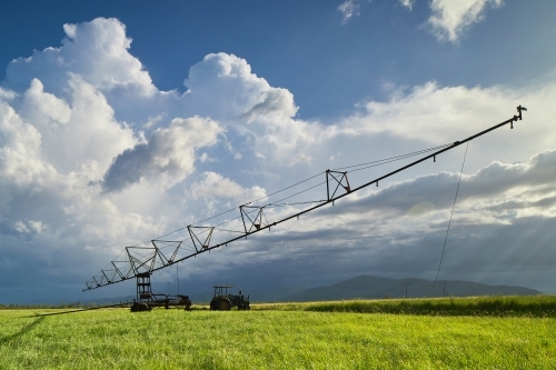 Farm irrigator sitting in paddock with storm clouds behind.