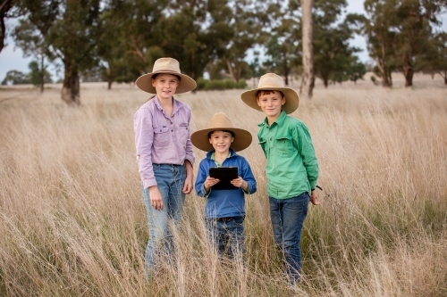 Farm kids in the paddock with an ipad - Australian Stock Image