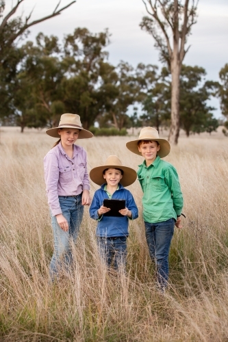 Farm kids using an ipad in the paddock - Australian Stock Image
