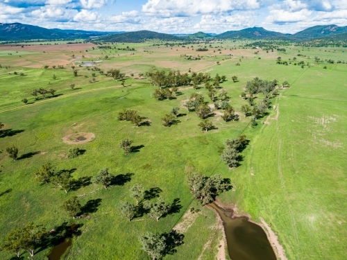 Farm landscape with dam and sunlit paddocks from the air - Australian Stock Image