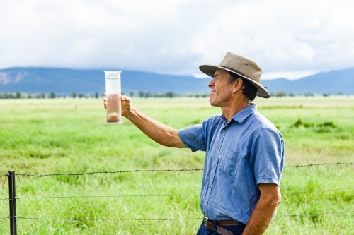 Farmer checking rain in bureau of meteorology rain gauge - Australian Stock Image
