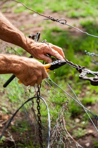 Farmer repairing fence so neighbours stock can't get through - Australian Stock Image