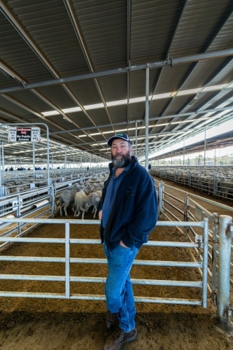 farmer standing in front of pen of sheep at Katanning saleyards