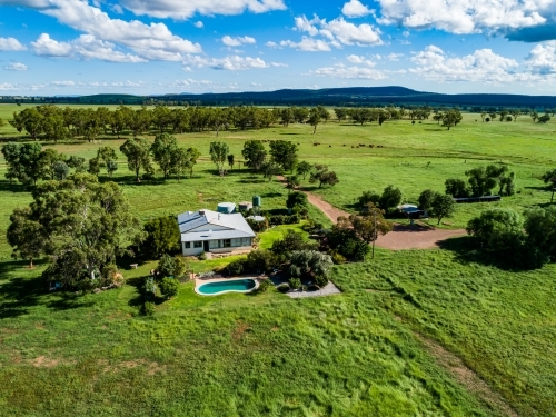 Farmhouse and pool on property among green paddocks - Australian Stock Image